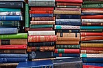 A great number of old, hard-backed books stacked on top of one another.