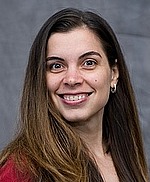 A professional headshot of Nina Balcan in front of a gray backdrop.  She is smiling and wearing a red shirt.