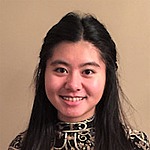A headshot of Gabrielle Kaili Liu.  She is smiling, wearing a mostly black shirt, and standing in front of a tan wall.