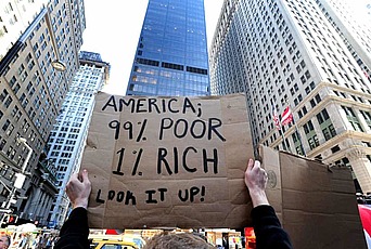 A demonstrator holds a sign that reads "America; 99% Poor, 1% Rich. Look it up!"