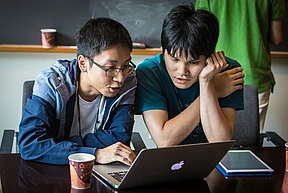 One person shows another something on the laptop screen