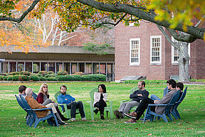 A small group sits on the lawn in discussion