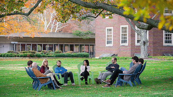 A small group sits on the lawn in discussion