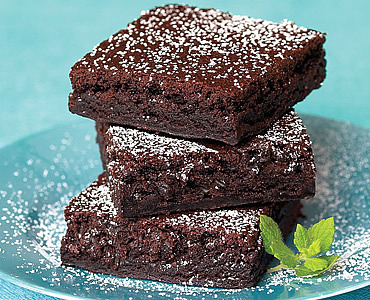 Stack of brownies sprinkled with powdered sugar on a plate.