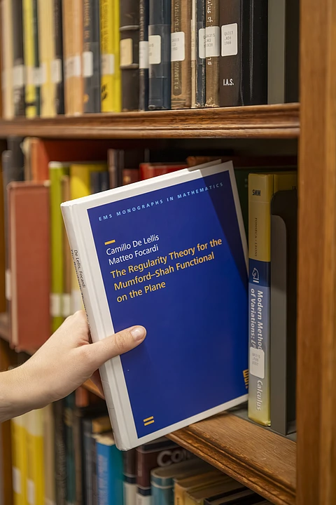 Math book being taken from bookshelf