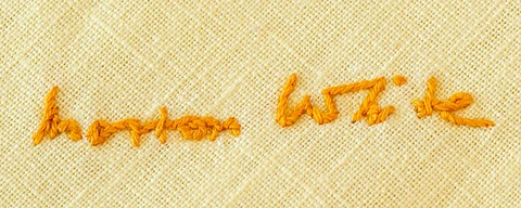 Orange embroidery of a signature on yellow fabric, showing cursive letters that read "Morton White"
